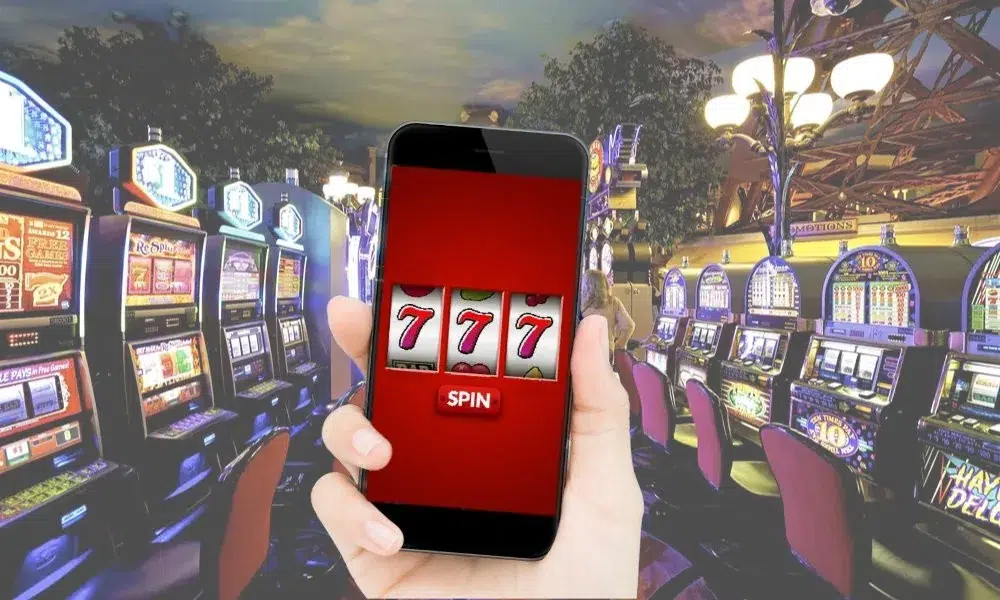 Sala da gioco reale con uno smartphone che mostra tre 7
